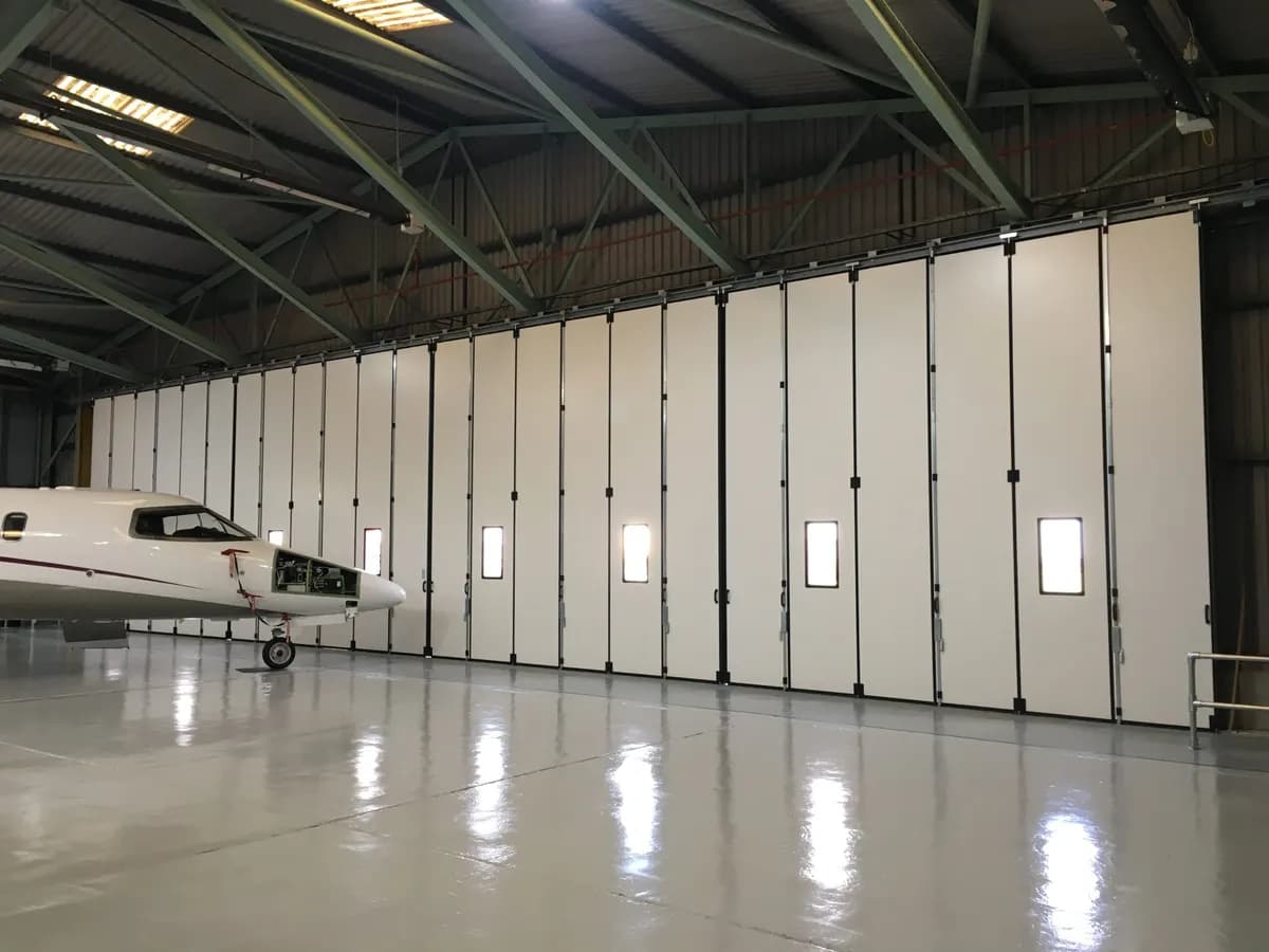 Porte pliante isolée à oculus fermant un hangar aéronautique, avion d’affaires stationné devant