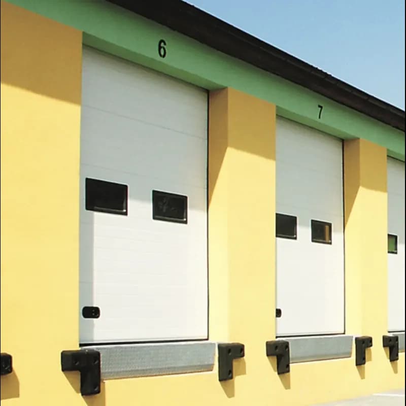 Quais de chargement numérotés équipés de portes sectionnelles blanches à hublots, avec butoirs et niveleurs de quai