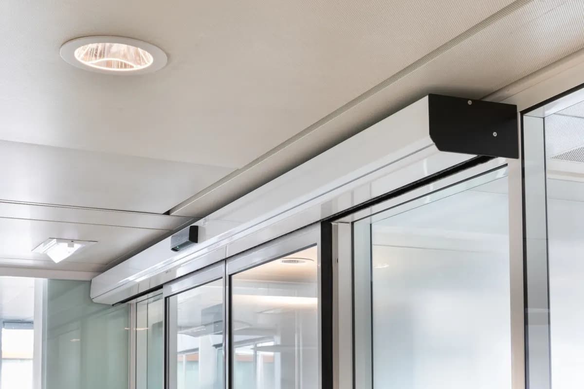 Bandeau opérateur aluminium d’une porte automatique coulissante, avec son capot d’extrémité et le radar de détection