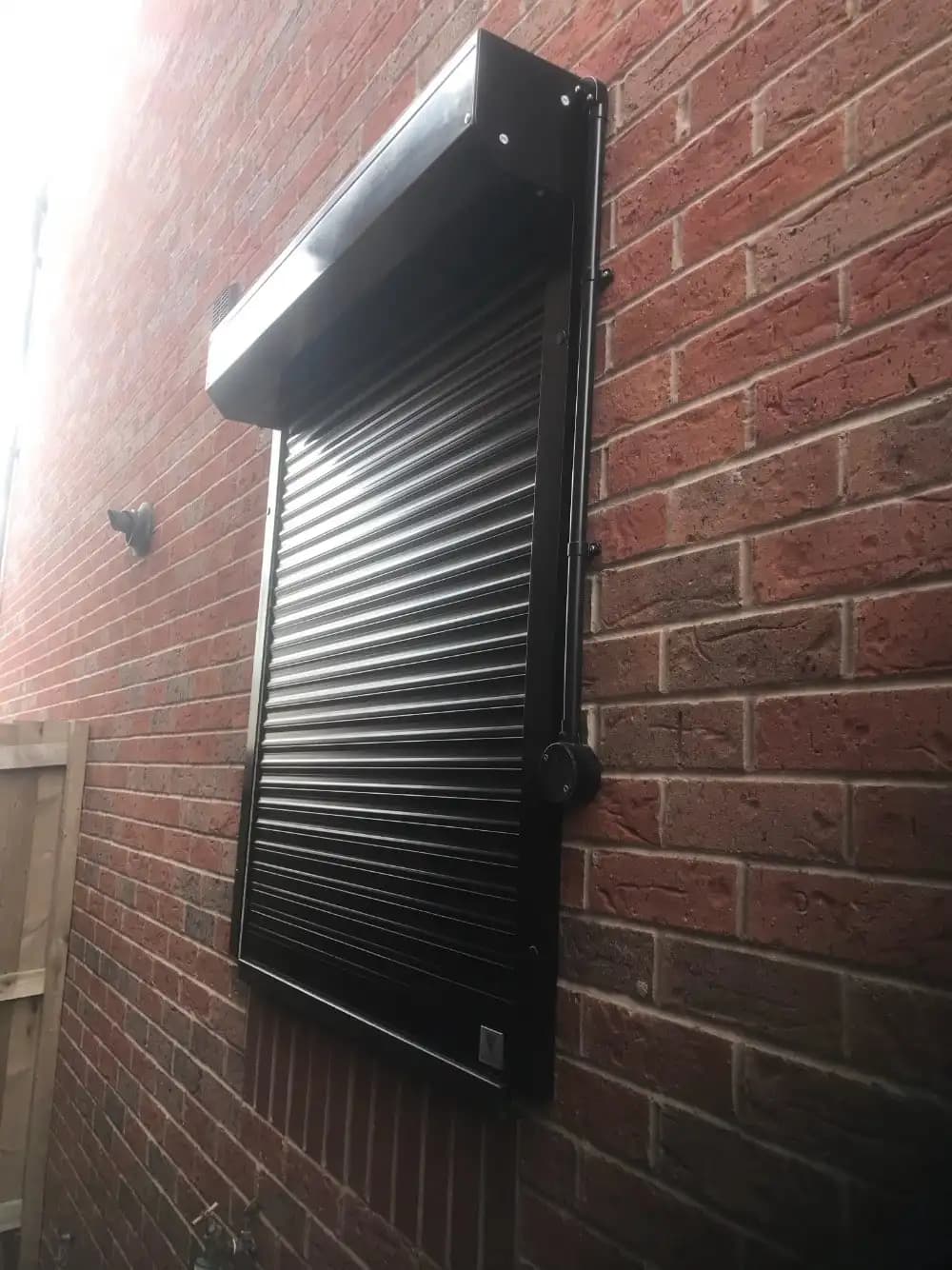 Caisson extérieur en aluminium thermolaqué noir d’un rideau extrudé, avec sa joue et l’axe d’enroulement