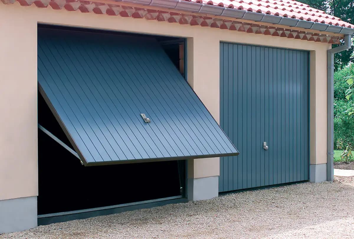 Porte basculante en position ouverte montrant le panneau monobloc basculé vers le haut et l’extérieur, à côté d’une porte identique fermée