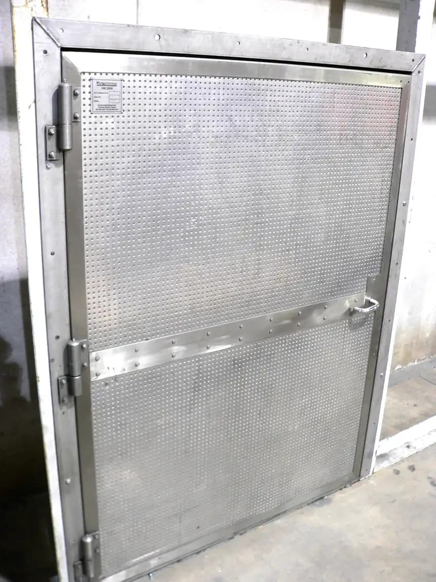 Porte battante industrielle en acier galvanisé entrouverte, montrant le vantail, le bâti soudé et les paumelles