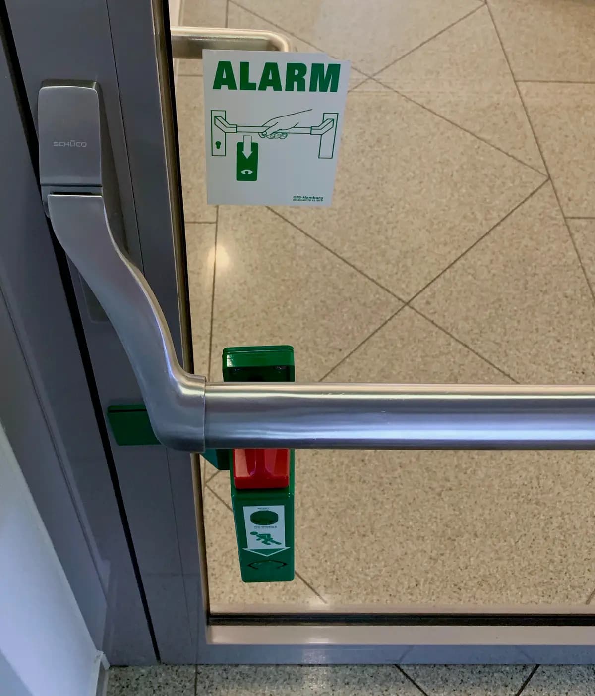 Barre anti-panique inox conforme EN 1125 montée sur un vantail, avec boîtier d’alarme de sortie de secours