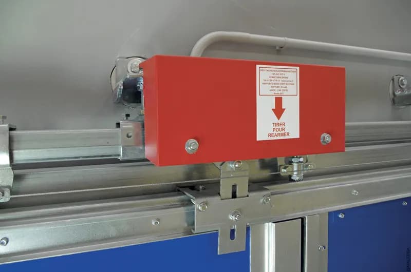 Tête de vantail coulissant montrant le rail, la platine de chariot et le boîtier électromagnétique de réarmement