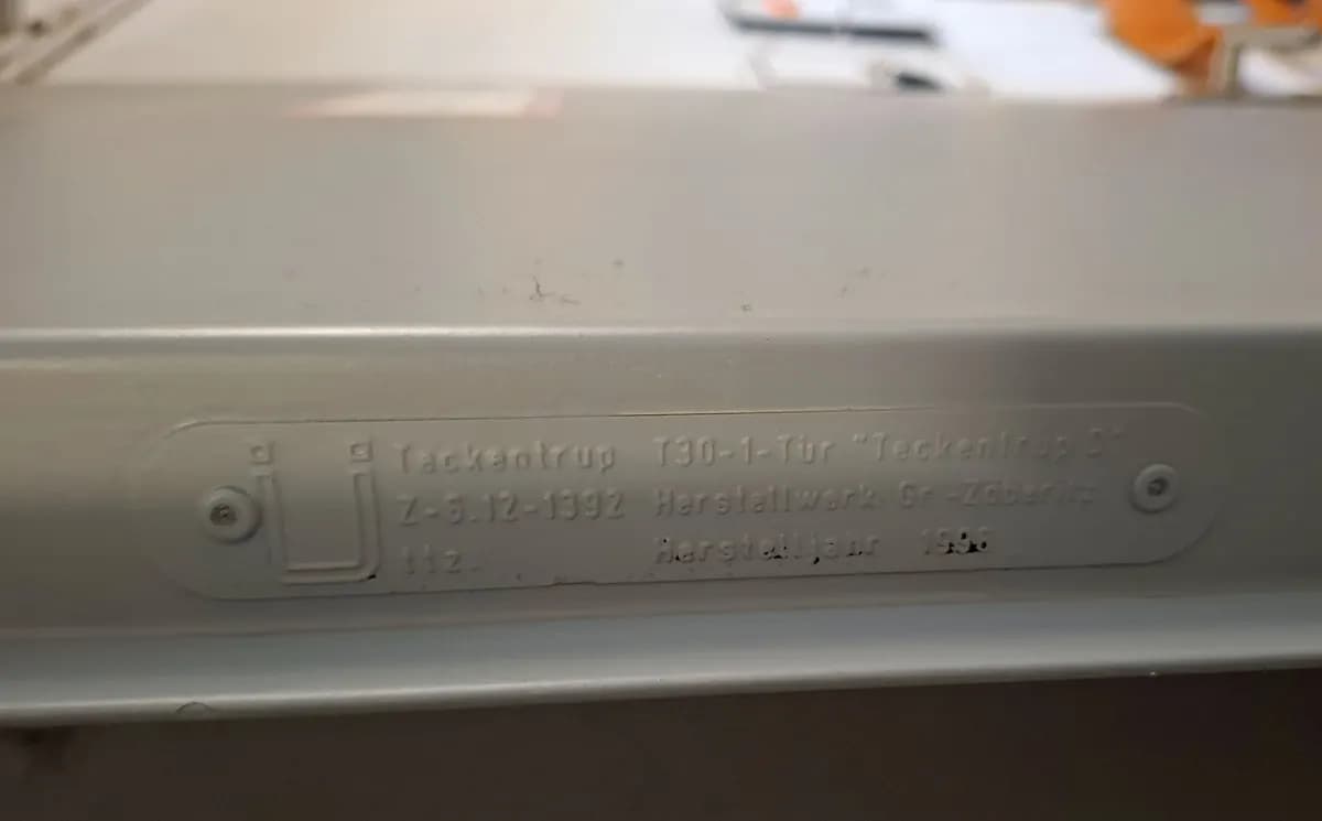 Plaque d’identification embossée sur la tranche d’un vantail coupe-feu, portant le type et les numéros d’agrément
