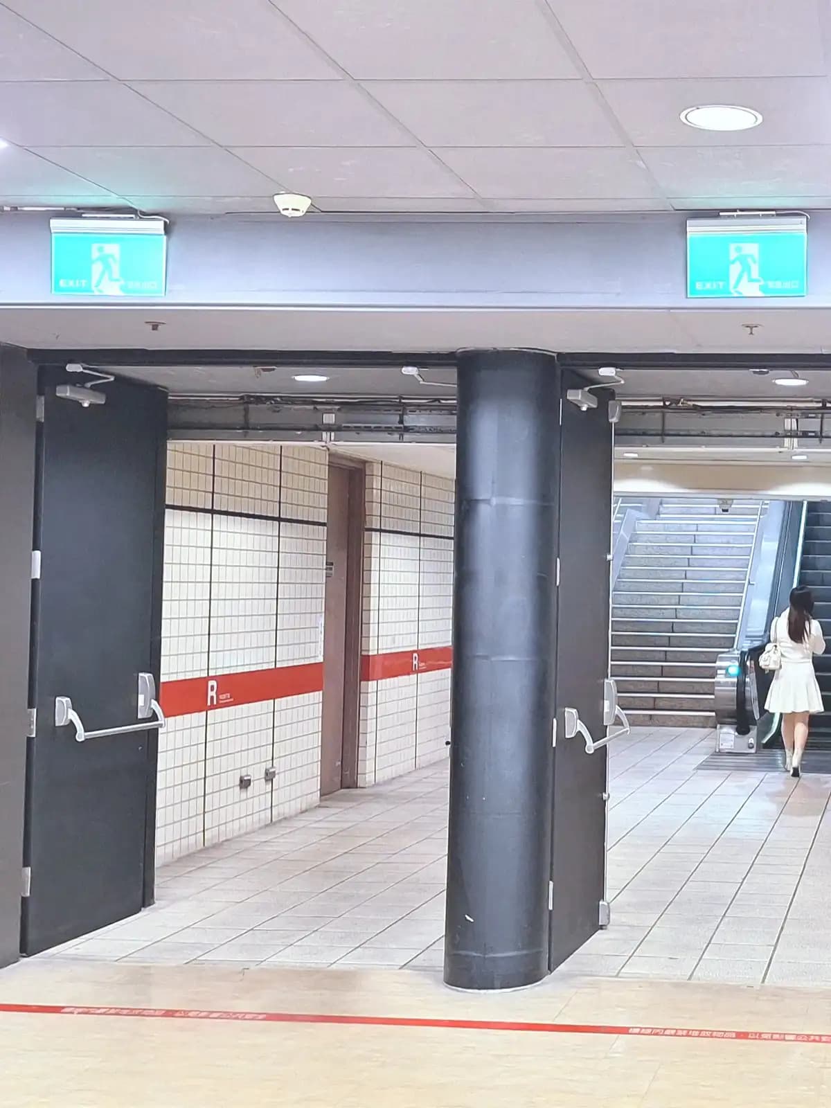 Bloc-porte coupe-feu à deux vantaux maintenu ouvert à une issue de centre commercial, barres anti-panique sur les deux vantaux