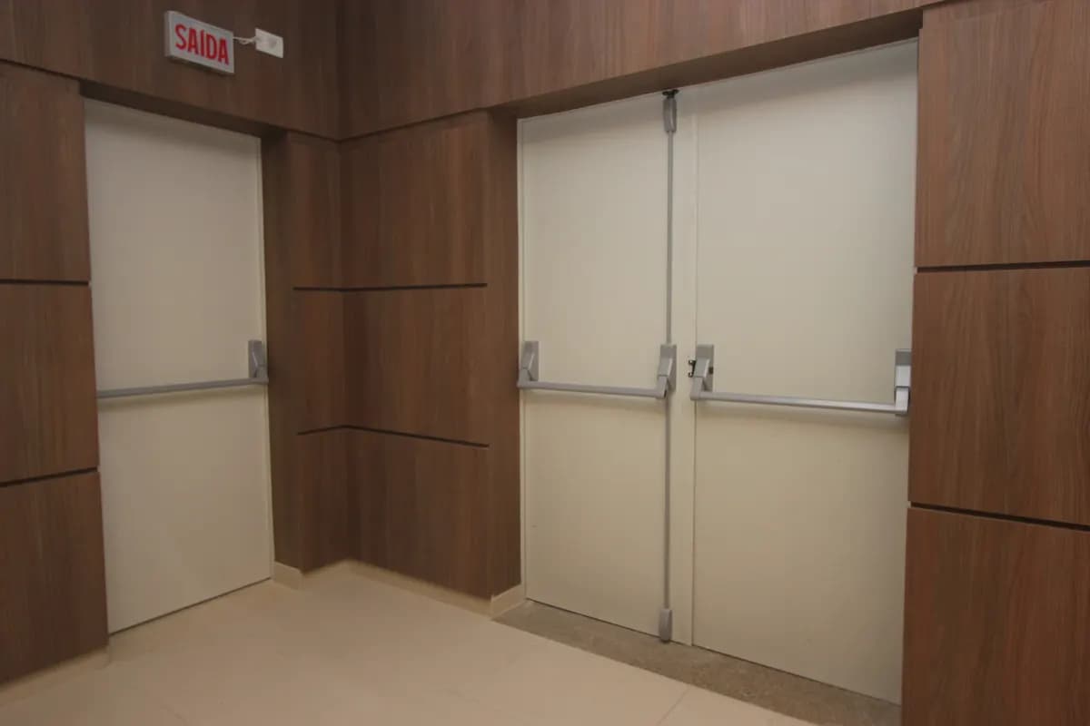 Variante : bloc-porte coupe-feu simple et double côte à côte dans un couloir, tous deux équipés de barres anti-panique horizontales