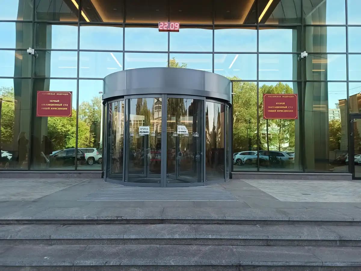 Porte tambour automatique à cylindre vitré complet et canopée aluminium, encastrée dans une façade en mur-rideau