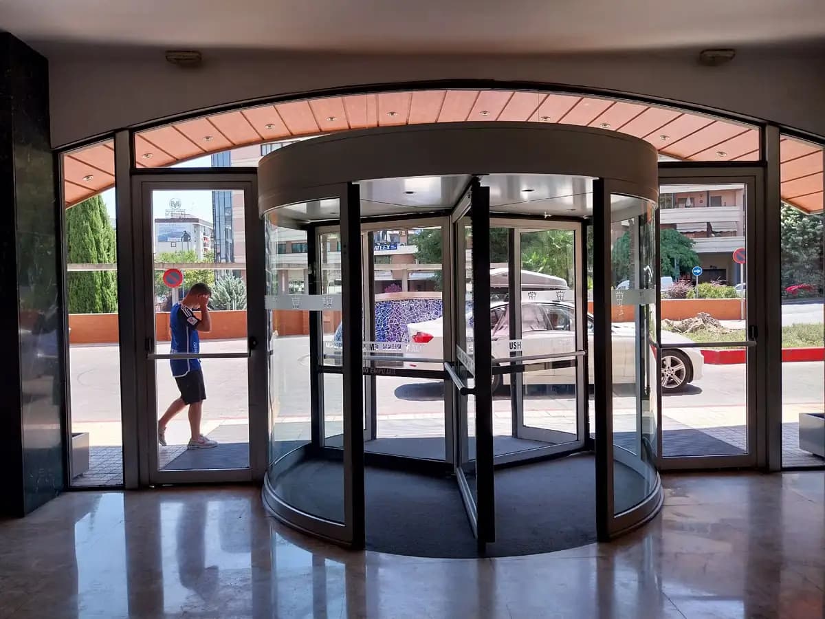 Vue intérieure d’une porte tournante à quatre vantaux : vantaux, meneau central et parois vitrées basses