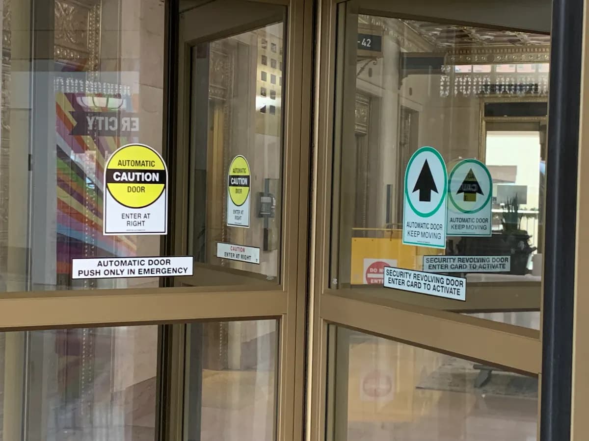 Signalétique de sécurité sérigraphiée sur les vantaux vitrés d’une porte tournante automatique à contrôle d’accès