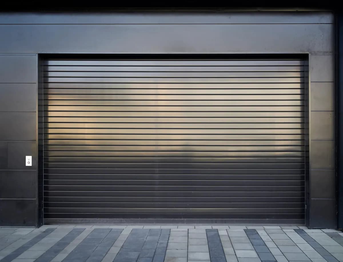 Rideau métallique anthracite à lames pleines entièrement fermé sur une ouverture commerciale en façade moderne