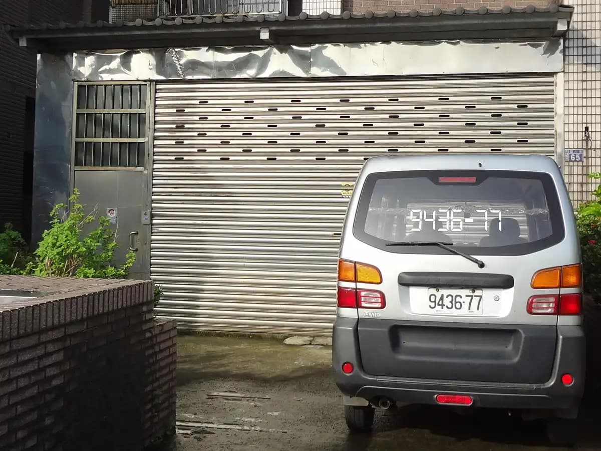 Variante à lames perforées : rideau métallique fermé sur un atelier-garage, ventilation naturelle assurée